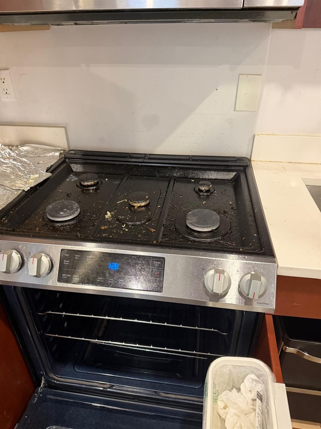Gas stovetop with burnt-on grease and food before a move-out deep cleaning